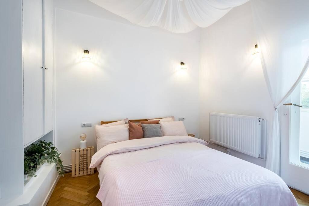 um quarto branco com uma cama grande e lençóis brancos em Downtown Cozy Apartment Old Town em Bucareste