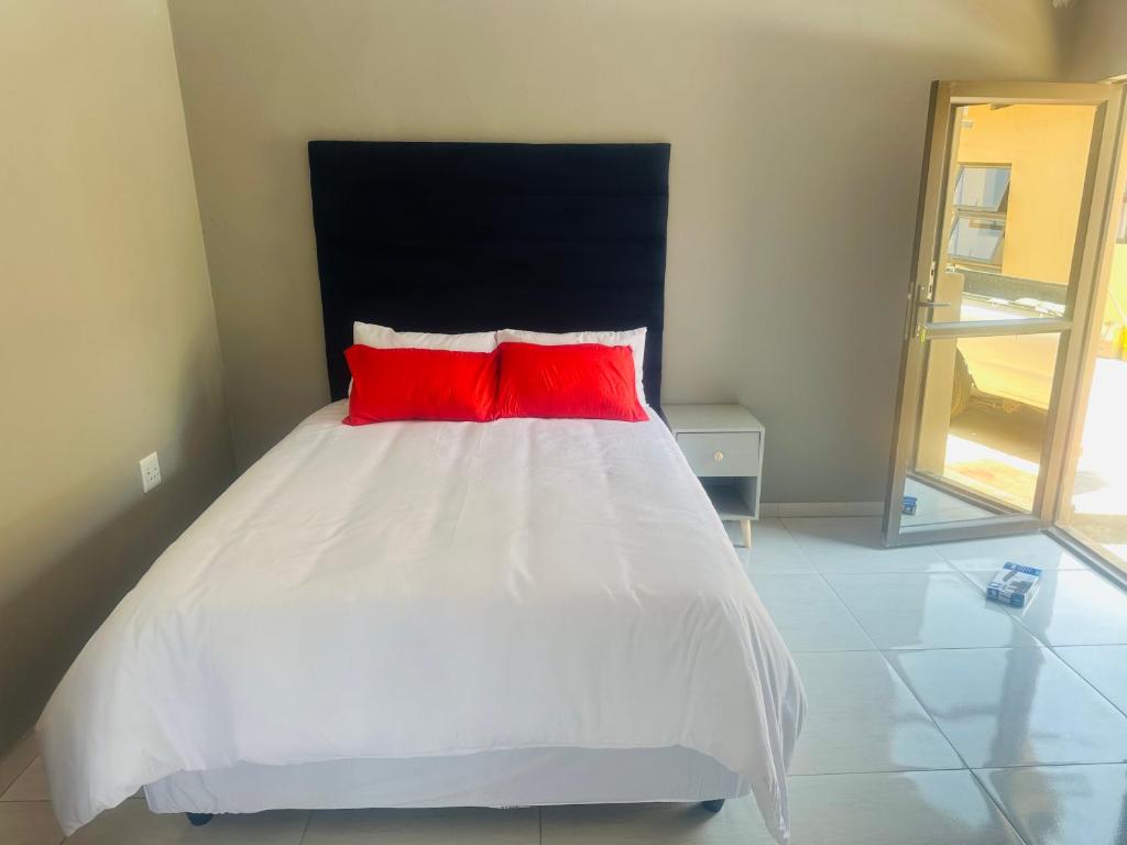 a bed with two red pillows in a room at Sweet Nice Guest House in Ga-Rankuwa