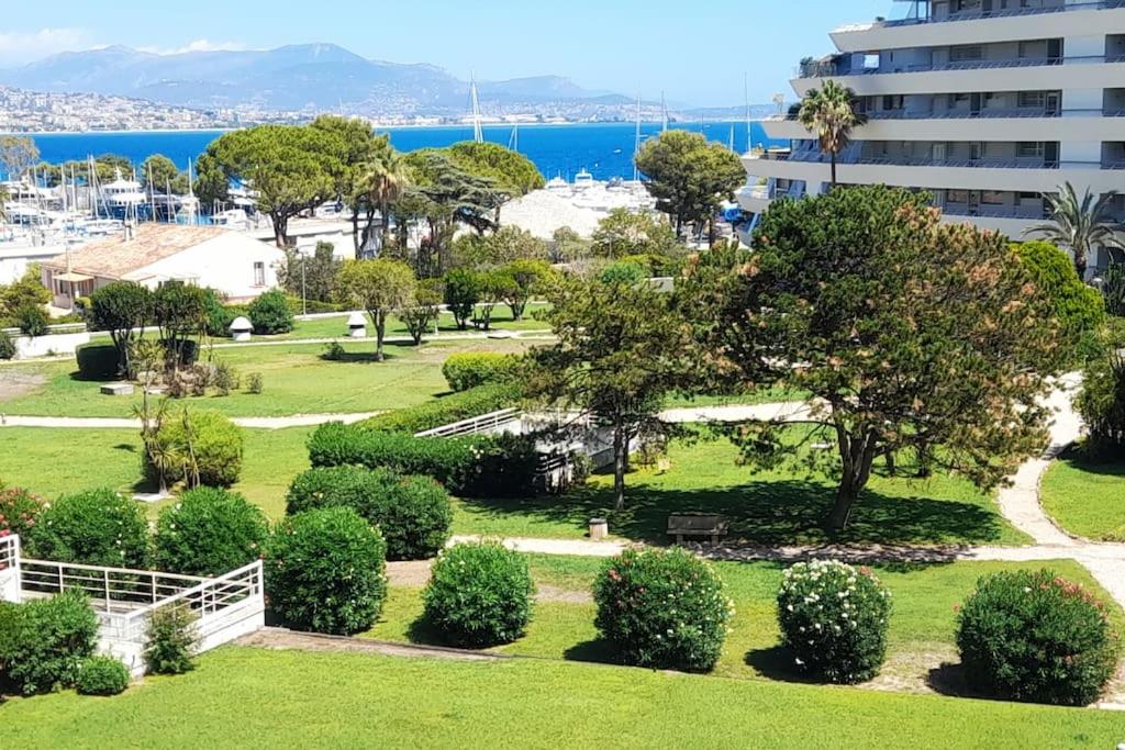 un parc avec des arbres et des buissons devant un bâtiment dans l'établissement Marina Baie des Anges, à Villeneuve-Loubet