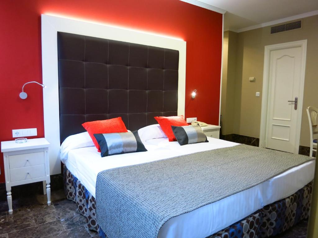 a bedroom with a large bed with a large headboard at Hotel Boutique Catedral in Valladolid