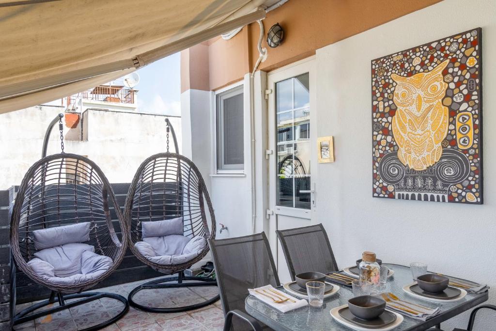 a patio with a table and chairs and a painting at The Owl - Stylish Penthouse - Gazi 1BDRM in Athens