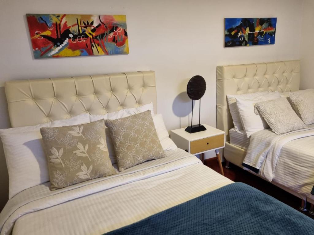 a bedroom with two beds and a painting on the wall at Florentina in Tunja