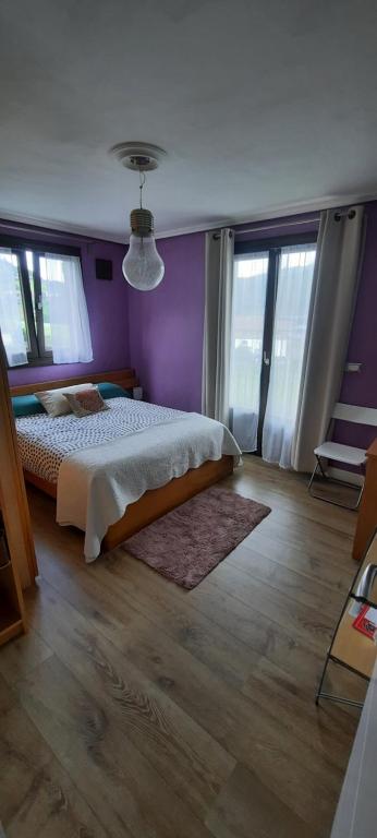 a bedroom with a bed and purple walls and windows at Abeletxe in Marquina