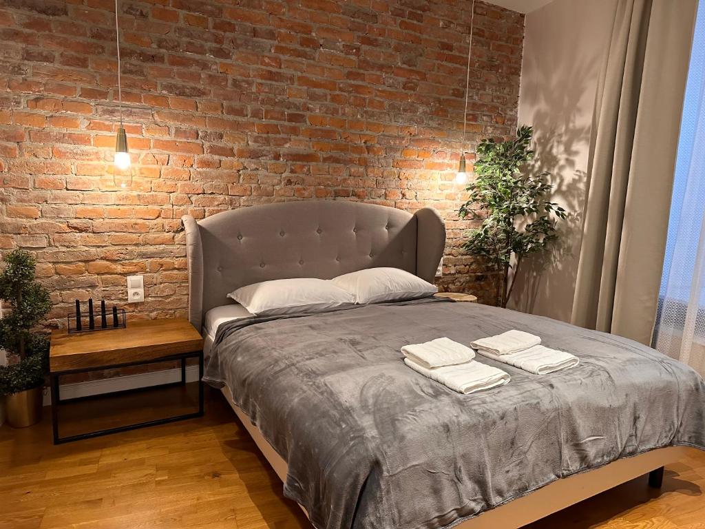 a bed in a room with a brick wall at Centrum Apartamenty Stare Miasto in Kraków