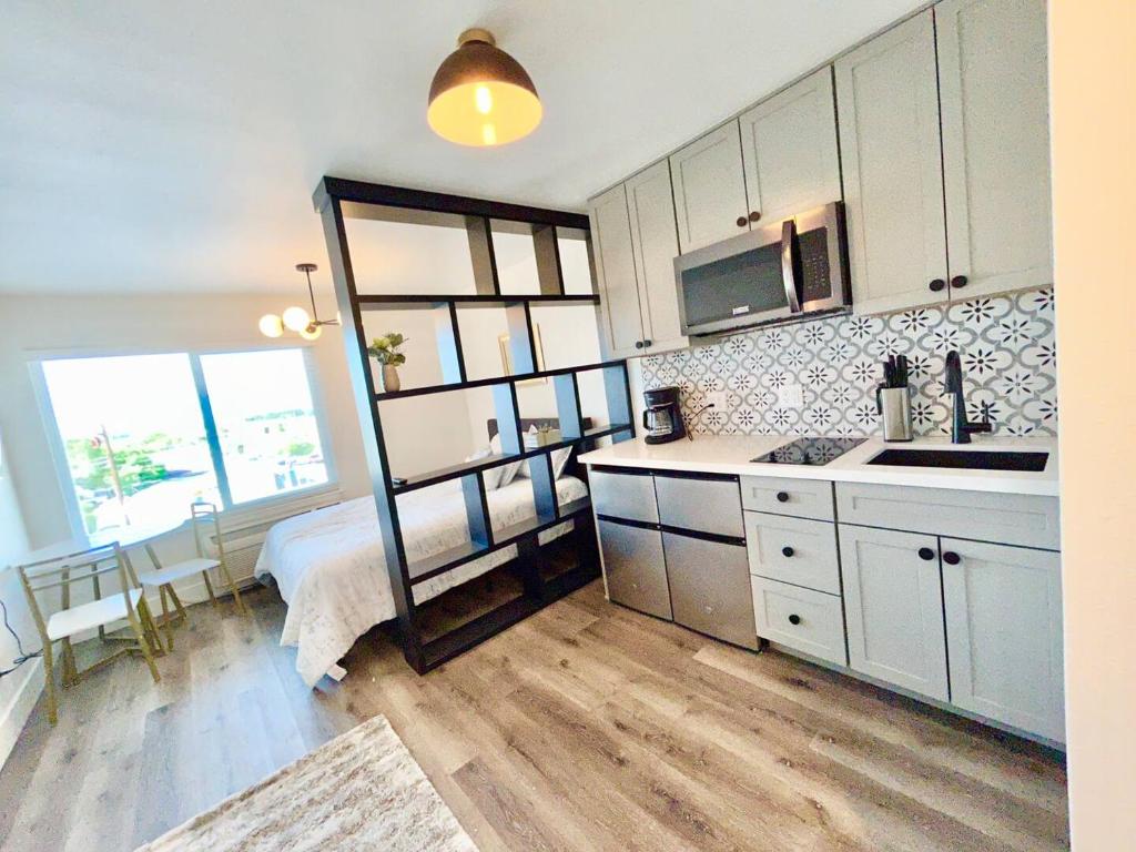 uma cozinha com armários brancos e uma cama num quarto em The Rivet Apartments em Reno