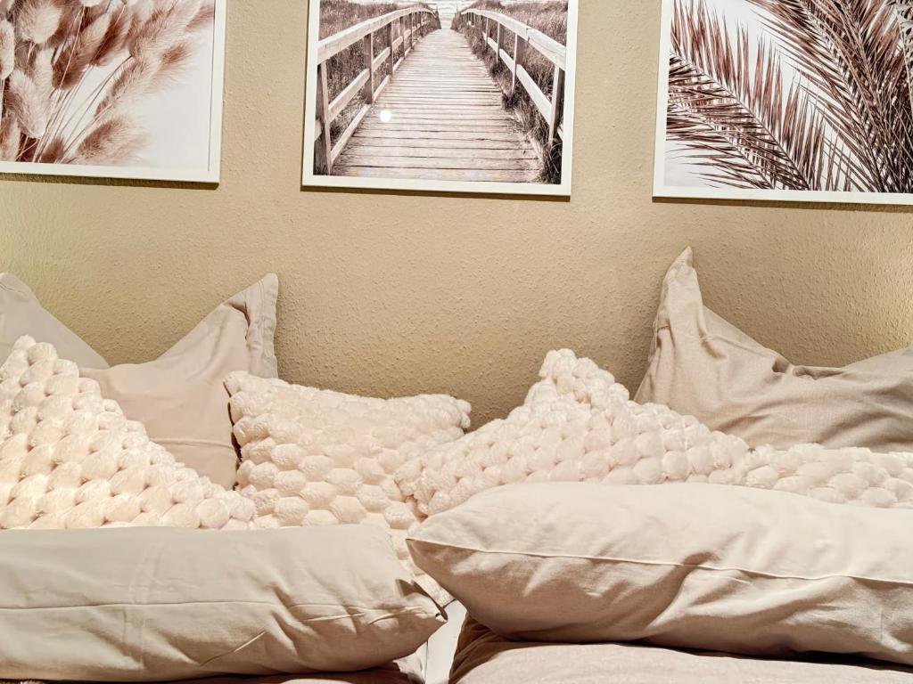 a bed with white pillows and pictures on the wall at Zwei Zimmer Natur und Luxus Ferienwohnung mit Garten in Schmilau