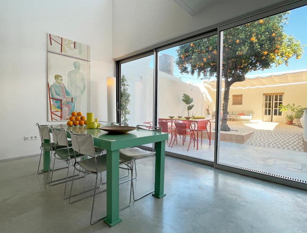 Carrión de los Céspedes的住宿－Design & art, patio with orange tree, near Seville，一间带绿色桌椅的用餐室