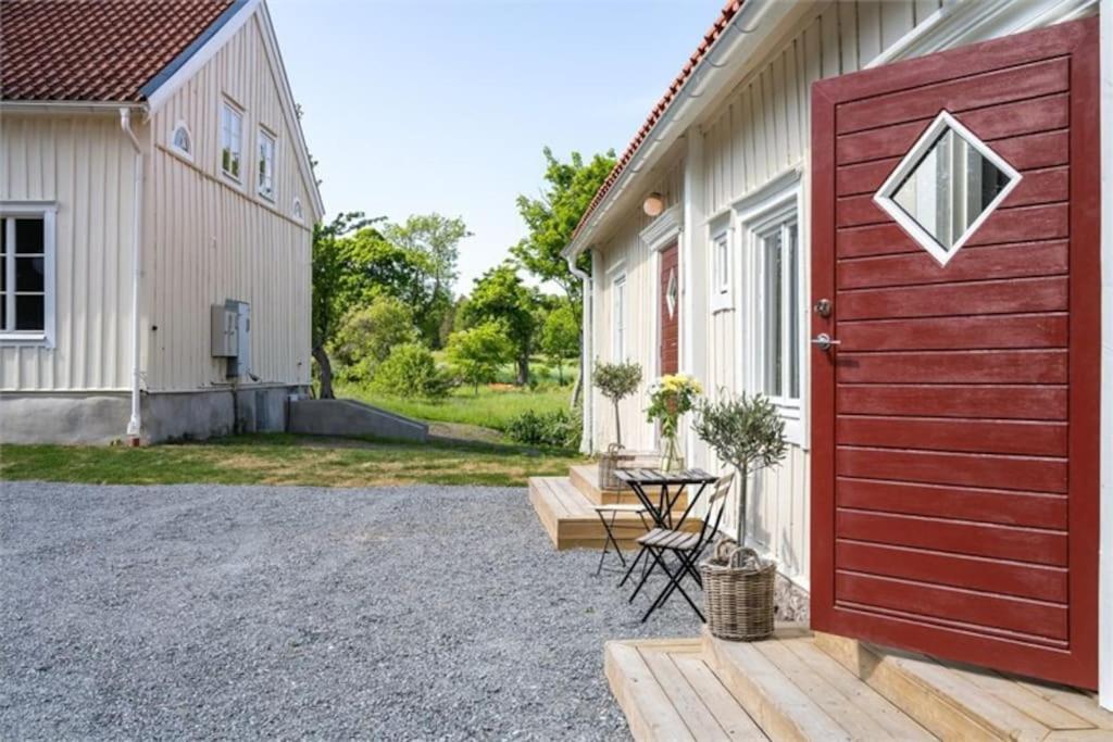 uma porta vermelha ao lado de uma casa em Prästgården i lantlig miljö med fyra sovrum, dusch, kök och vardagsrum em Knivsta