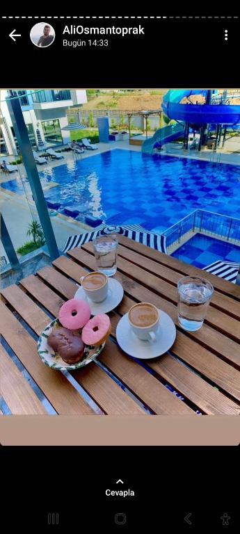 dos donuts y bebidas en una mesa junto a una piscina en Exodos park, en Alanya