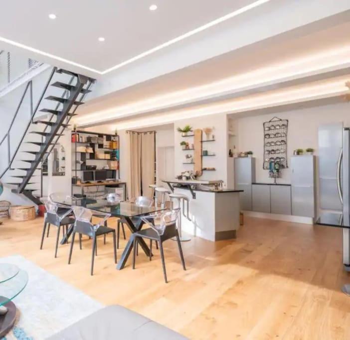 un salon avec une table et des chaises et un escalier dans l'établissement Loft design & familial parc des Buttes Chaumont, à Paris