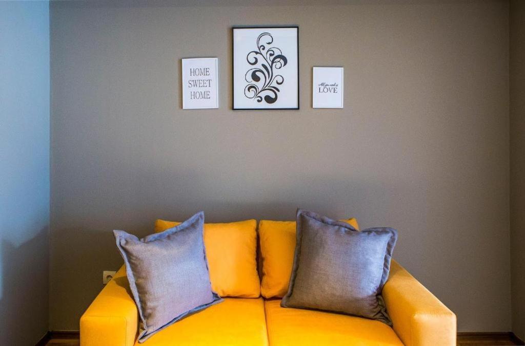 a yellow couch with three pillows in a living room at N.Joy Holiday Apartment 417 by Sunny Hills in Pamporovo