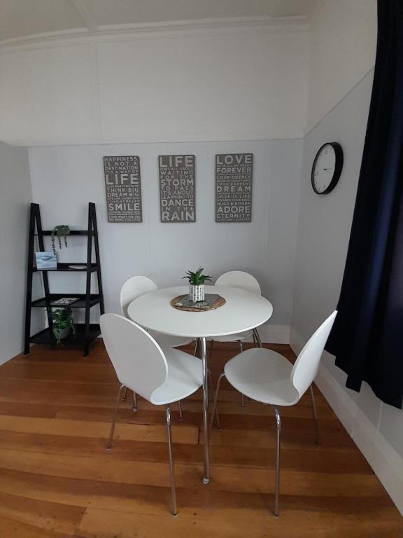 a table and chairs in a room with a clock at Character 1-Bedroom Unit in Masterton