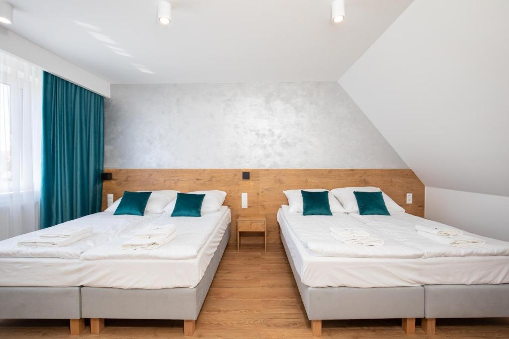 two beds in a room with blue pillows at Gorczański Zakątek in Konina