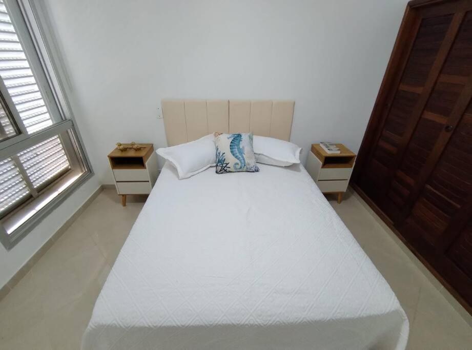 - une chambre avec un lit blanc et 2 tables de chevet dans l'établissement Apto Pitangueiras vista para o Mar, à Guarujá