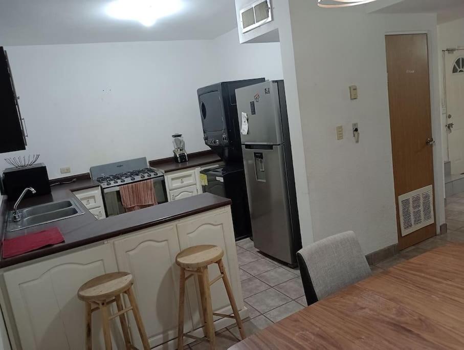 uma cozinha com um frigorífico e 2 bancos de bar em Casa Puente del Zorro em Ciudad Juárez