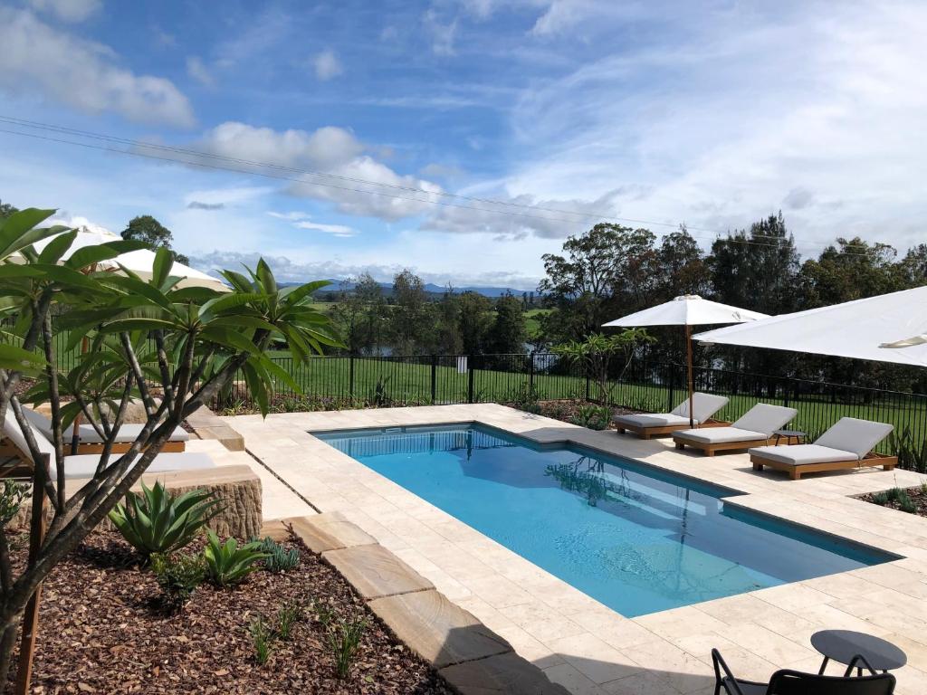 a swimming pool with two chairs and an umbrella at Mansfield on the Manning in Tinonee