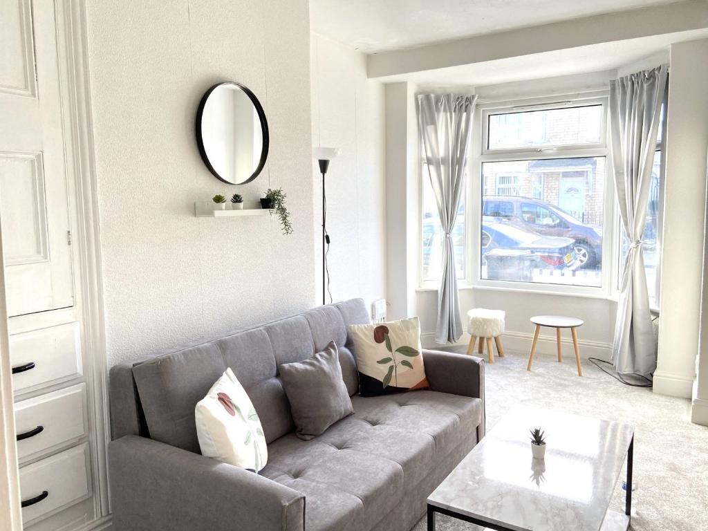 uma sala de estar com um sofá cinzento e um espelho em Kisobi Home Bedroom 1 em Hull