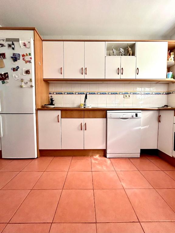 a kitchen with white cabinets and a white refrigerator at Casa Caracol in La Herradura