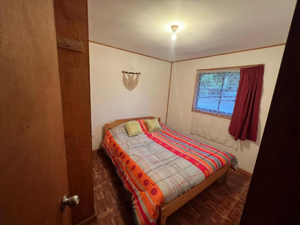 Habitación pequeña con cama y ventana en cabaña Wenu Mapu queule, en Queule