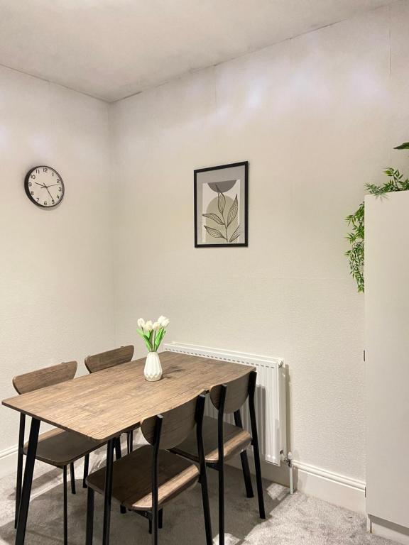 Una mesa de comedor con sillas y un reloj en la pared. en Kisobi Home Bedroom 2, en Hull