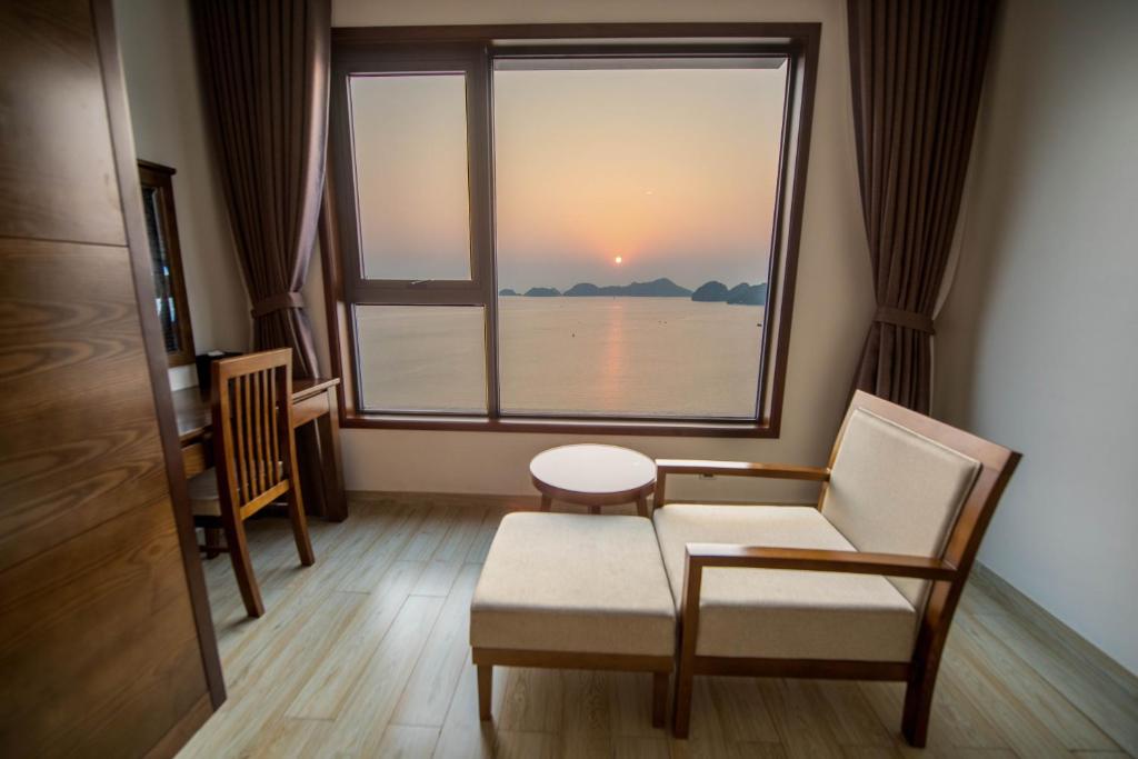 a room with a chair and a window with a sunset at Cat ba Paradise Hotel - Sky Bar & Massage in Cat Ba