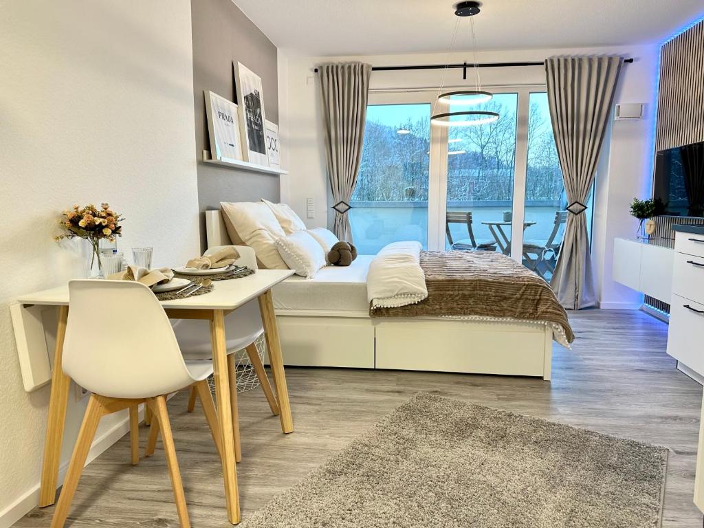 a bedroom with a bed and a table and a dining room at Modernes Apartment inkl. TG-Stellplatz in der Nähe zum Bahnhof - YUKA Apartments in Schwäbisch Hall