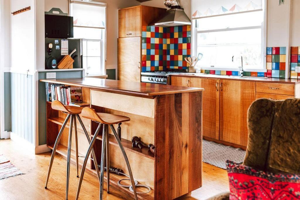 a kitchen with a wooden counter and stools in it at s u n s e t s h a c k Binalong in Binalong Bay