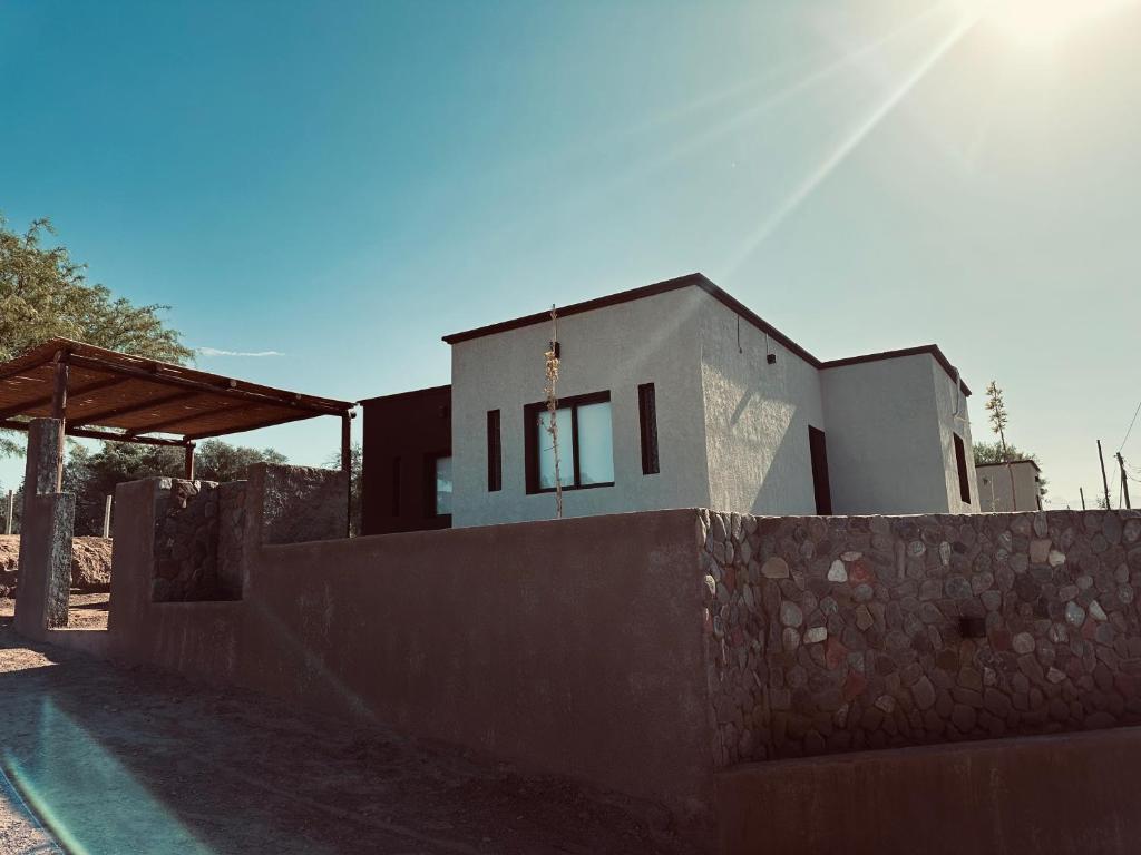 una casa detrás de una pared de piedra con una valla en LaChuwy Casas en Villa Unión
