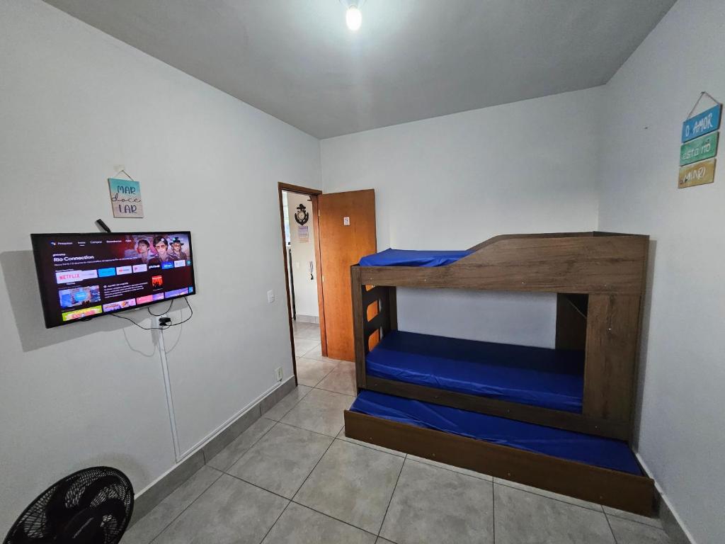 a room with a bed and a flat screen tv at Apartamento 2 Quartos Bertioga WVM in Bertioga