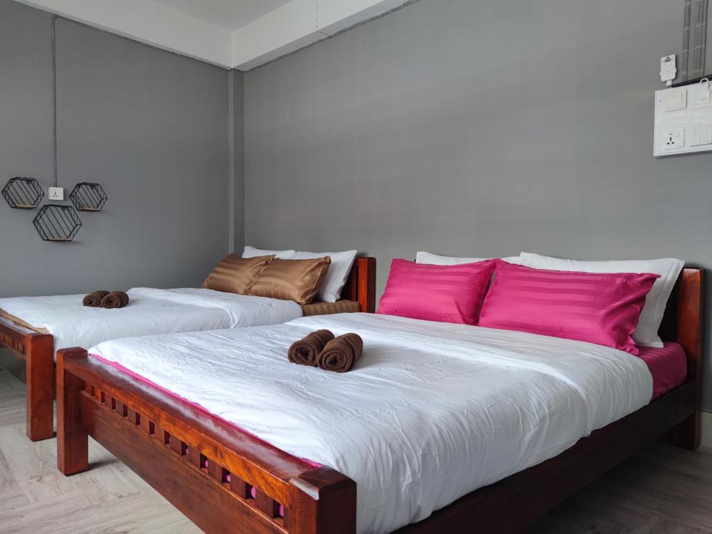 two twin beds in a room with pink pillows at Zamanja Betong106 Main Street in Yala
