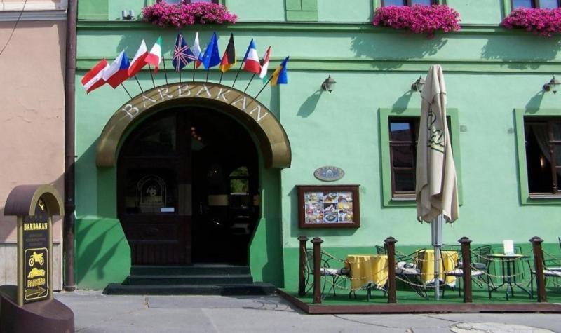 ein grünes Gebäude mit einem Tisch mit Flaggen darauf in der Unterkunft Hotel Barbakan in Levoča