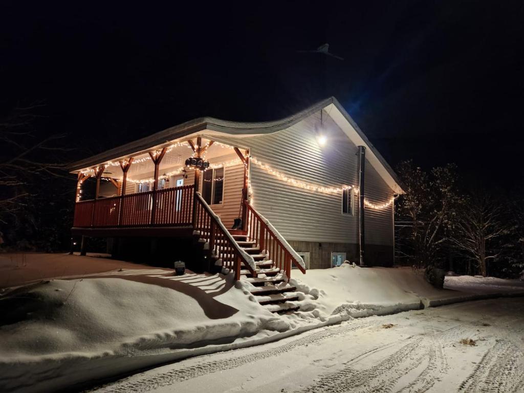 een huis met verlichting in de sneeuw bij Havre de détente avec foyer et spa in Sainte-Lucie-de-Doncaster