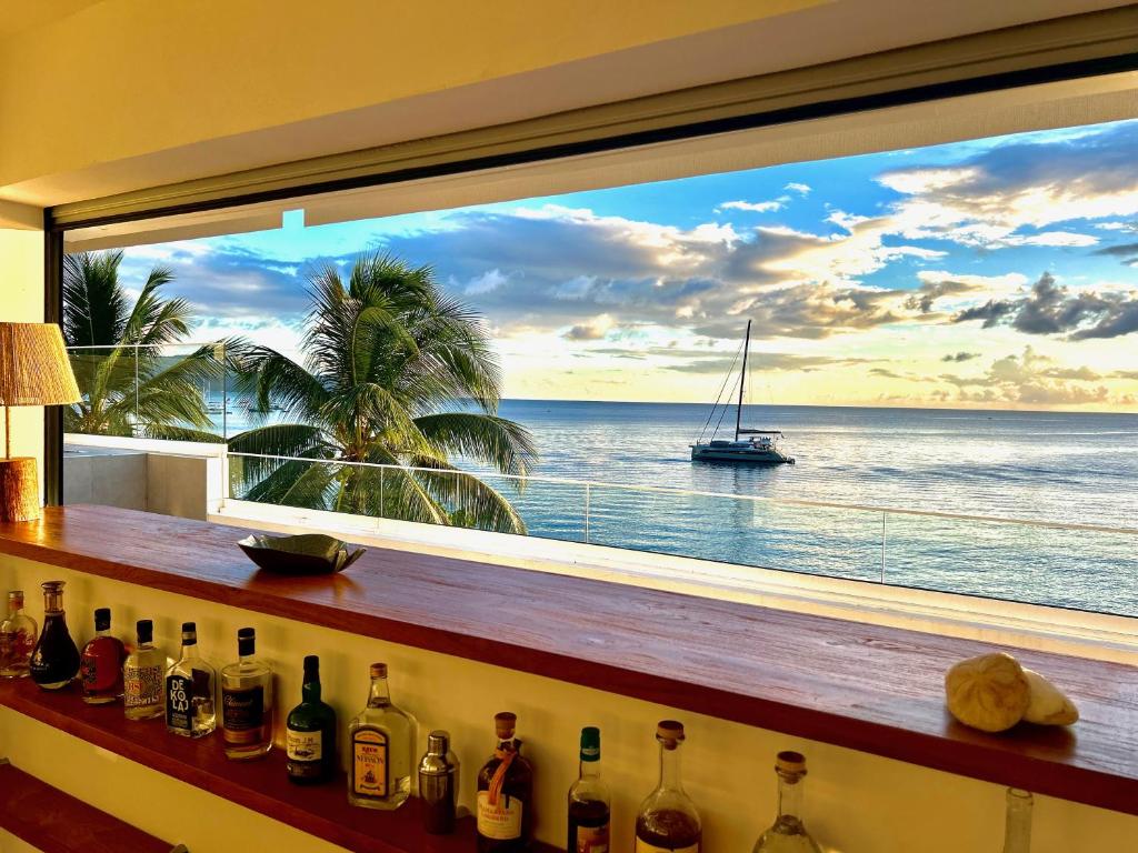 a window with a view of the ocean and a boat at LA PLAGE MARTINIQUE in Schœlcher