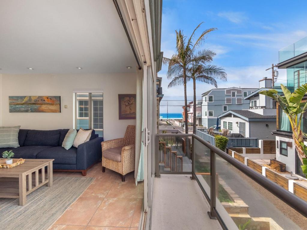 ein Wohnzimmer mit einem Sofa und einem Tisch auf dem Balkon in der Unterkunft Ocean View Beach Haven! Steps2Beach & Pet Friendly in San Diego