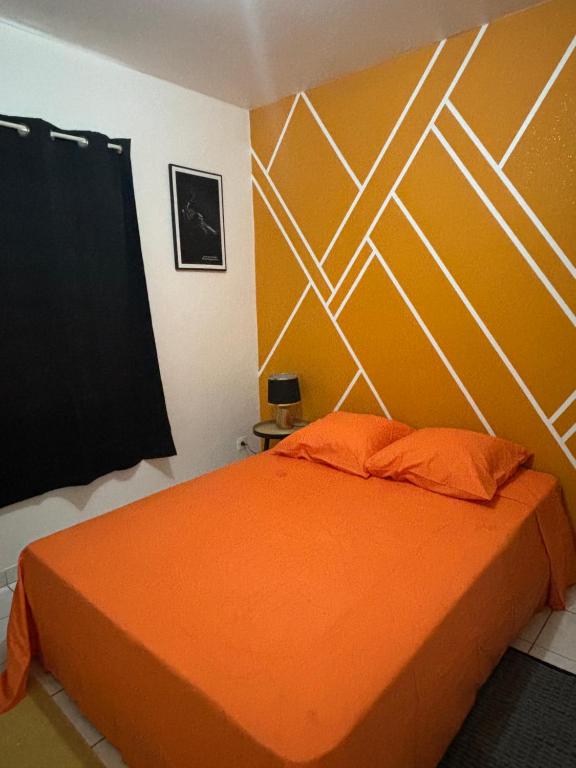 um quarto com uma cama com uma colcha laranja em Appartement or em Caiena