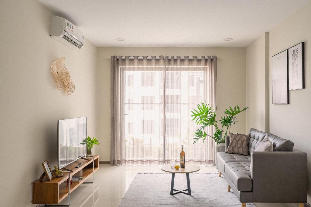 una sala de estar con un sofá y una mesa en Roomio De Capella - Share Apartment, en Ho Chi Minh