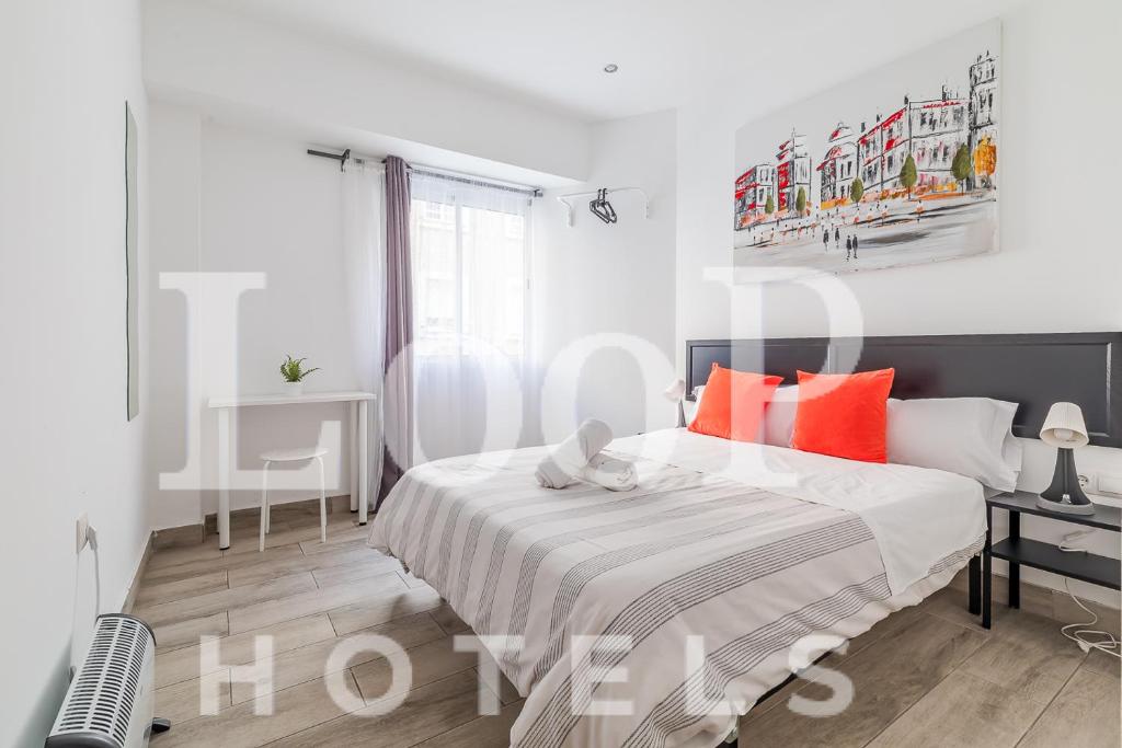 マドリードにあるLooP Las Ventasの白いベッドルーム(オレンジ色の枕が付くベッド付)