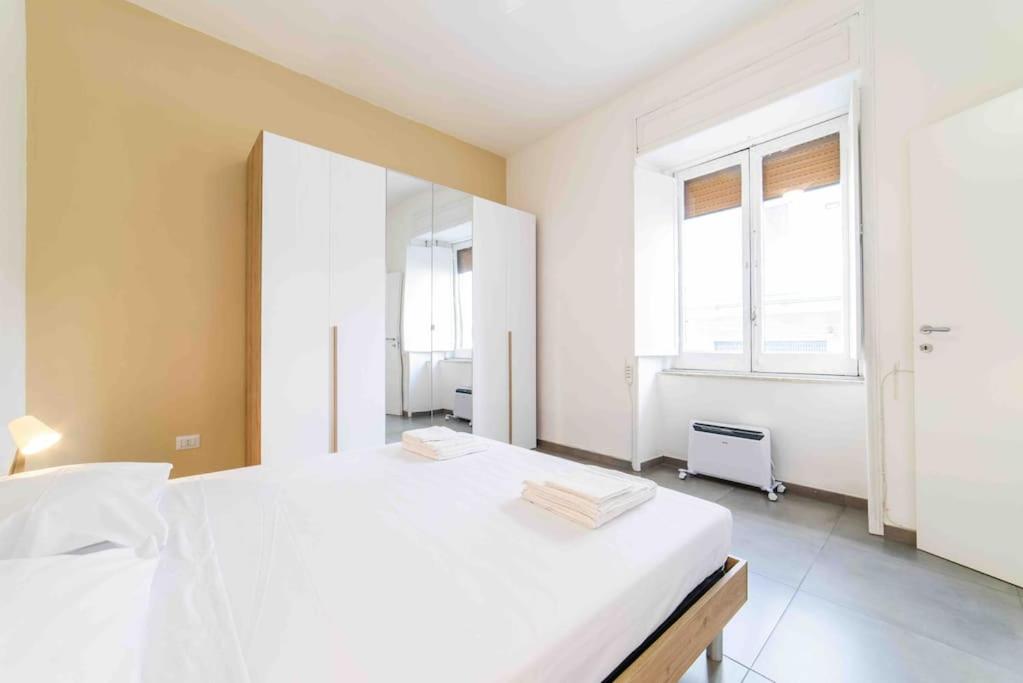 1 Schlafzimmer mit einem großen weißen Bett und 2 Fenstern in der Unterkunft [Incantevole Bilocale] Wi-Fi + Netflix in Salerno