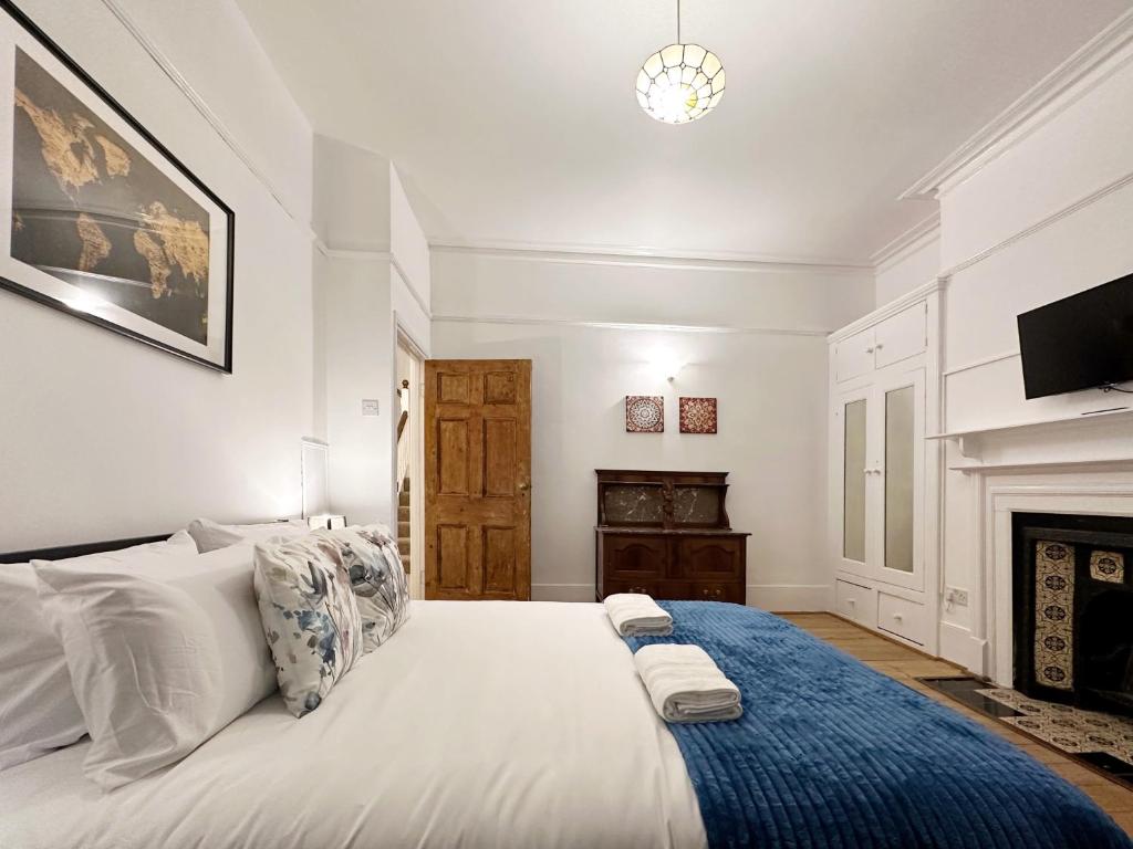 a white bedroom with a large bed and a fireplace at Hannah’s Place Near Finsbury Park in London