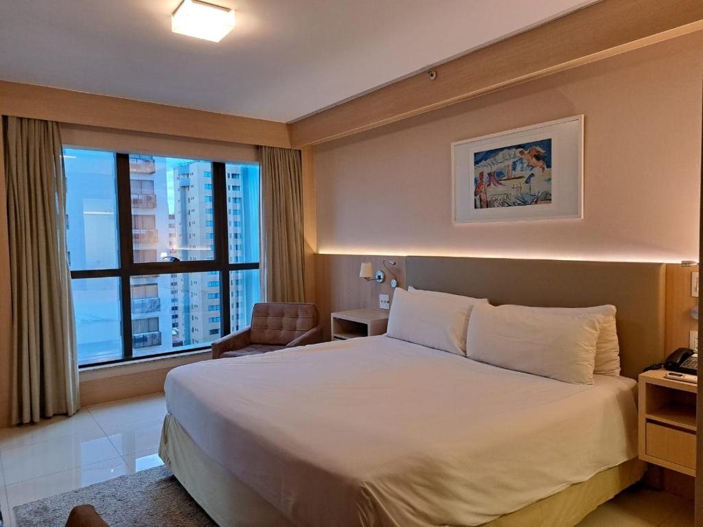 a hotel room with a bed and a large window at BSB STAY Flats particulares - CULLINAN in Brasilia