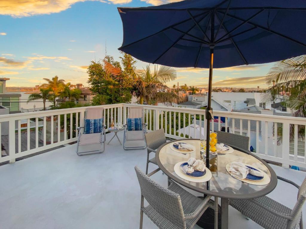 a table and chairs on a balcony with an umbrella at Bay View Paradise - Rooftop Deck, Off-Street Parking, King Suite, WasherDryer & Bay Views! in San Diego