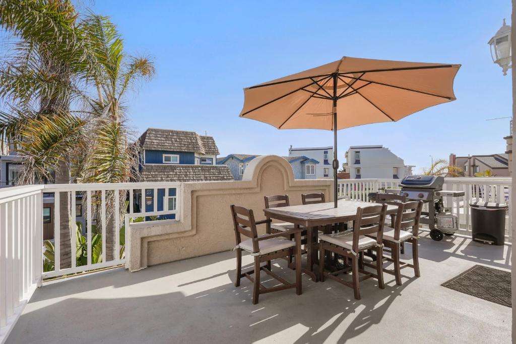 a table and chairs with an umbrella on a balcony at Stunning Beach Home with Fireplace, Fast WiFi, Grill & Outdoor Seating! in San Diego