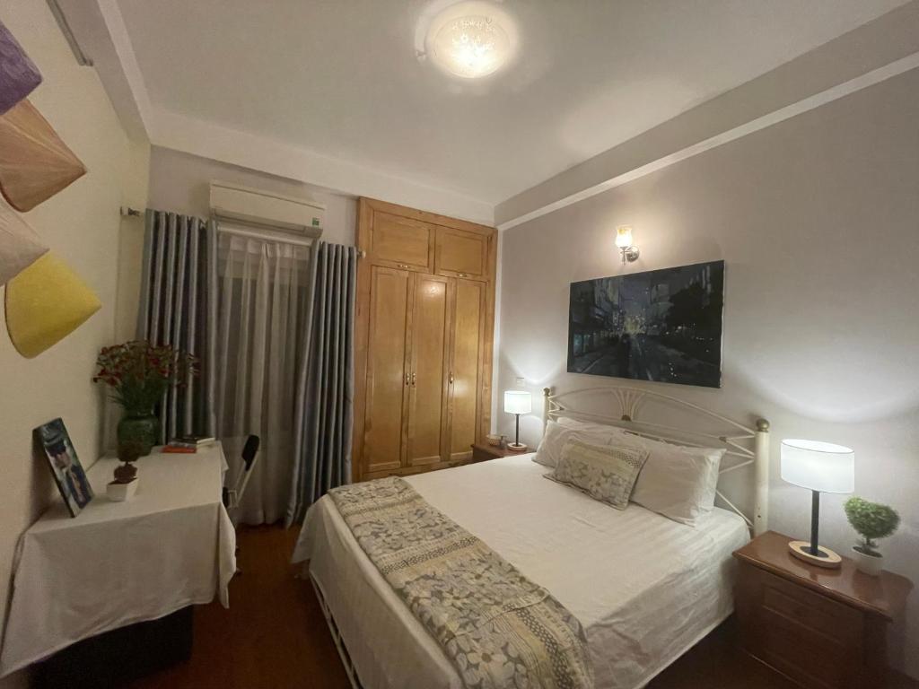 um quarto com uma cama branca e 2 candeeiros em Long Bien Homestay em Hanói