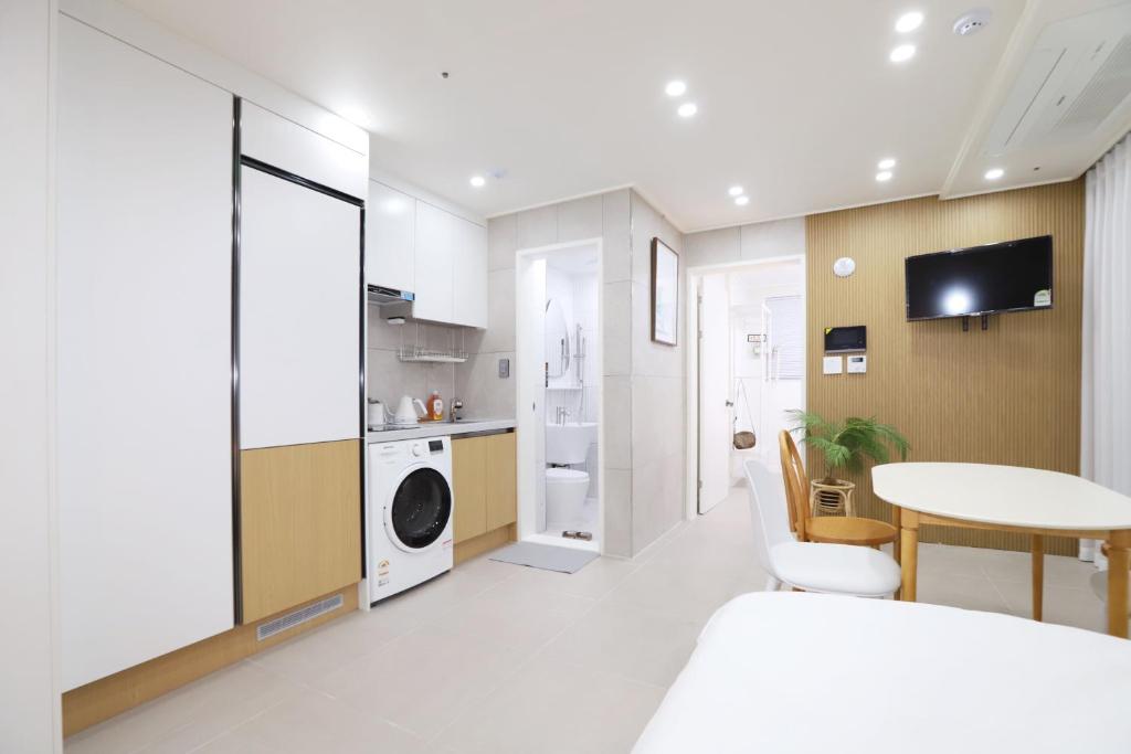 biała kuchnia z pralką i suszarką w obiekcie Apartment_Trust w Seulu
