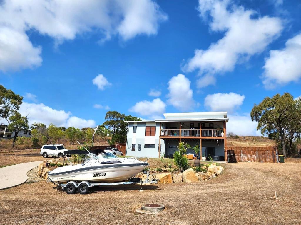 a boat is parked in front of a house at Bowen Sunrise Retreat Homestay in Bowen