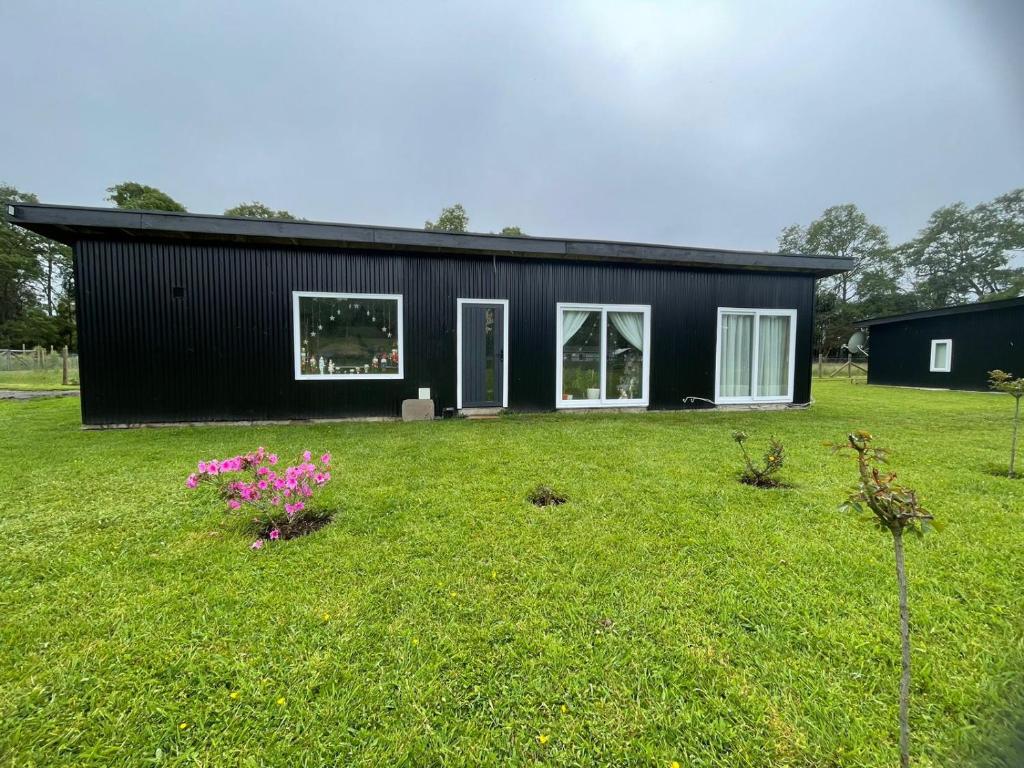 a black house with a yard with flowers at Casa en Lago Ranco in Ignao