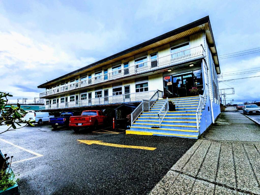 a building with blue and white stairs in a parking lot at Aleeda Motel in Prince Rupert