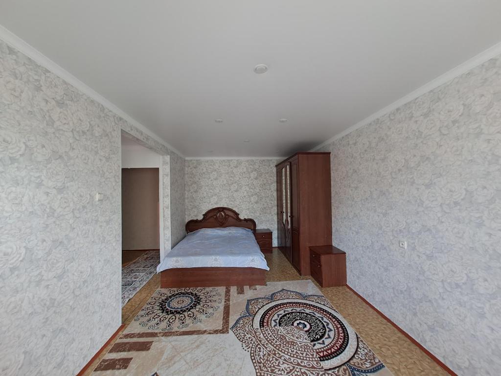 ein Schlafzimmer mit einem Bett und einem Teppich auf dem Boden in der Unterkunft 408 квартал in Semei