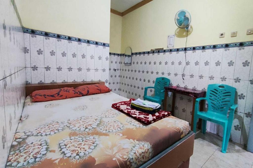 - une chambre avec un lit et deux chaises bleues dans l'établissement OYO 93396 Pondok Wisata Sri Mulyo, à Yogyakarta