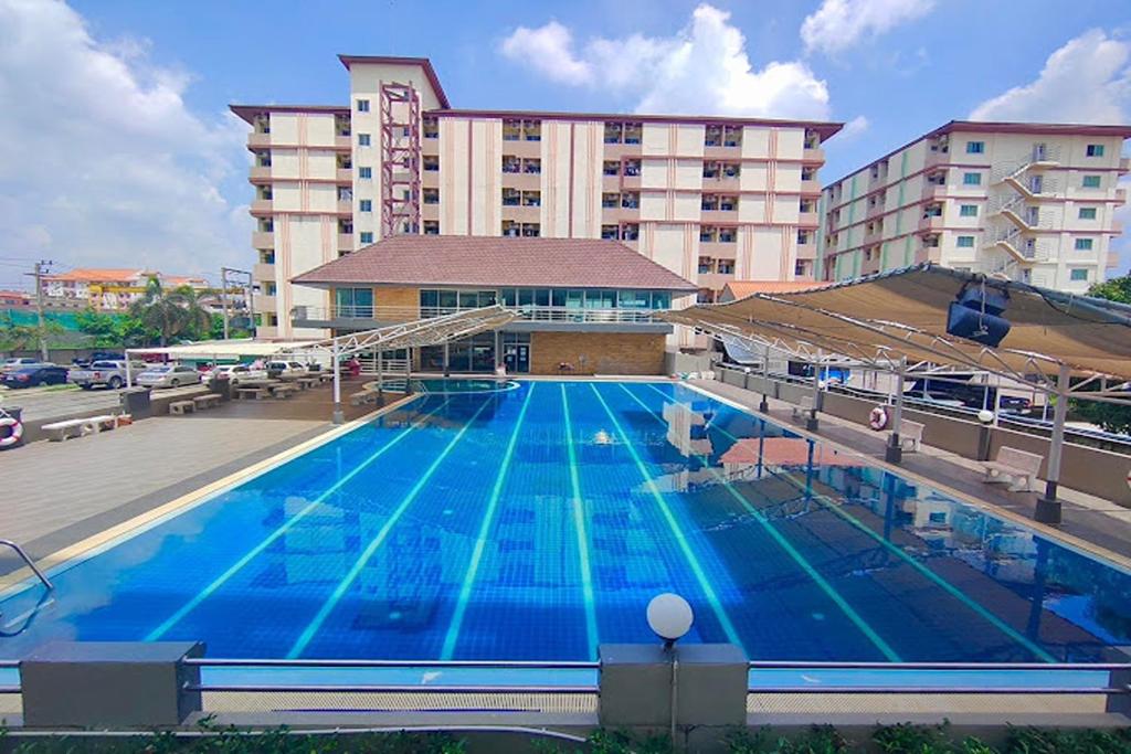 a large swimming pool in front of a hotel at ONE Residence in Pathum Thani